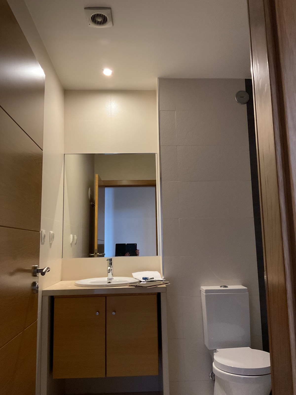 Estado anterior à remodelação — zona de lavatório com móvel de fundo claro, espelho simples e ausência de organização